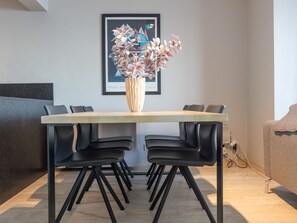 A modern dining area with a wooden table, black chairs, and a vase with flowers. - Apartment on the Seventh Floor With sea View (Middelkerke)