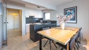 Una cocina moderna con una isla central, un comedor con mesa y sillas de madera, y una obra de arte enmarcada en la pared.