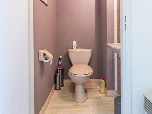 A bathroom with a toilet, a toilet paper holder, a trash can, and a bottle of cleaning product. - Apartment on the Seventh Floor With sea View (Middelkerke)