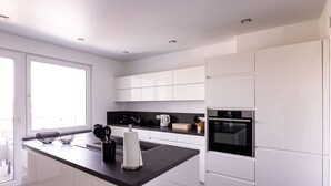 A modern kitchen with white cabinetry, a black countertop, and a built-in oven. - Apartment for 6 Modern Retreat (Andernach)