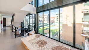 A modern interior with a staircase, large windows, and a view of a courtyard. - Apartment in Asturias Near Playa de Torimbia (Llanes)