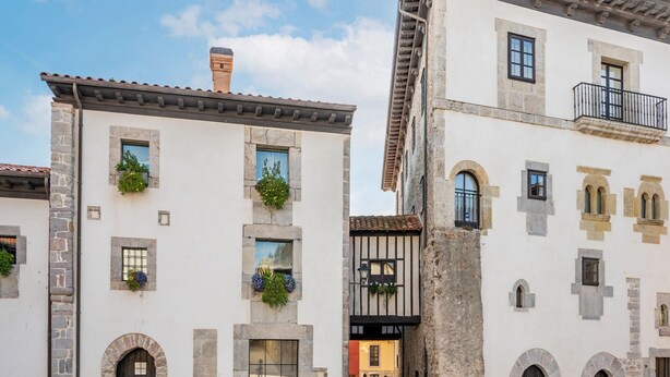 A traditional European-style building with stone facades, arched doorways, and a central entrance with a black door. - Apartment in Asturias Near Playa de Torimbia (Llanes)