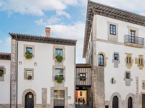 Un edificio de estilo europeo tradicional con fachadas de piedra, arcos en las entradas y una puerta negra en el acceso principal.