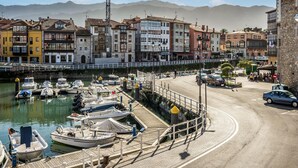 A marina with boats docked, a construction crane, and colorful buildings along the waterfront. - Apartment in Asturias Near Playa de Torimbia (Llanes)