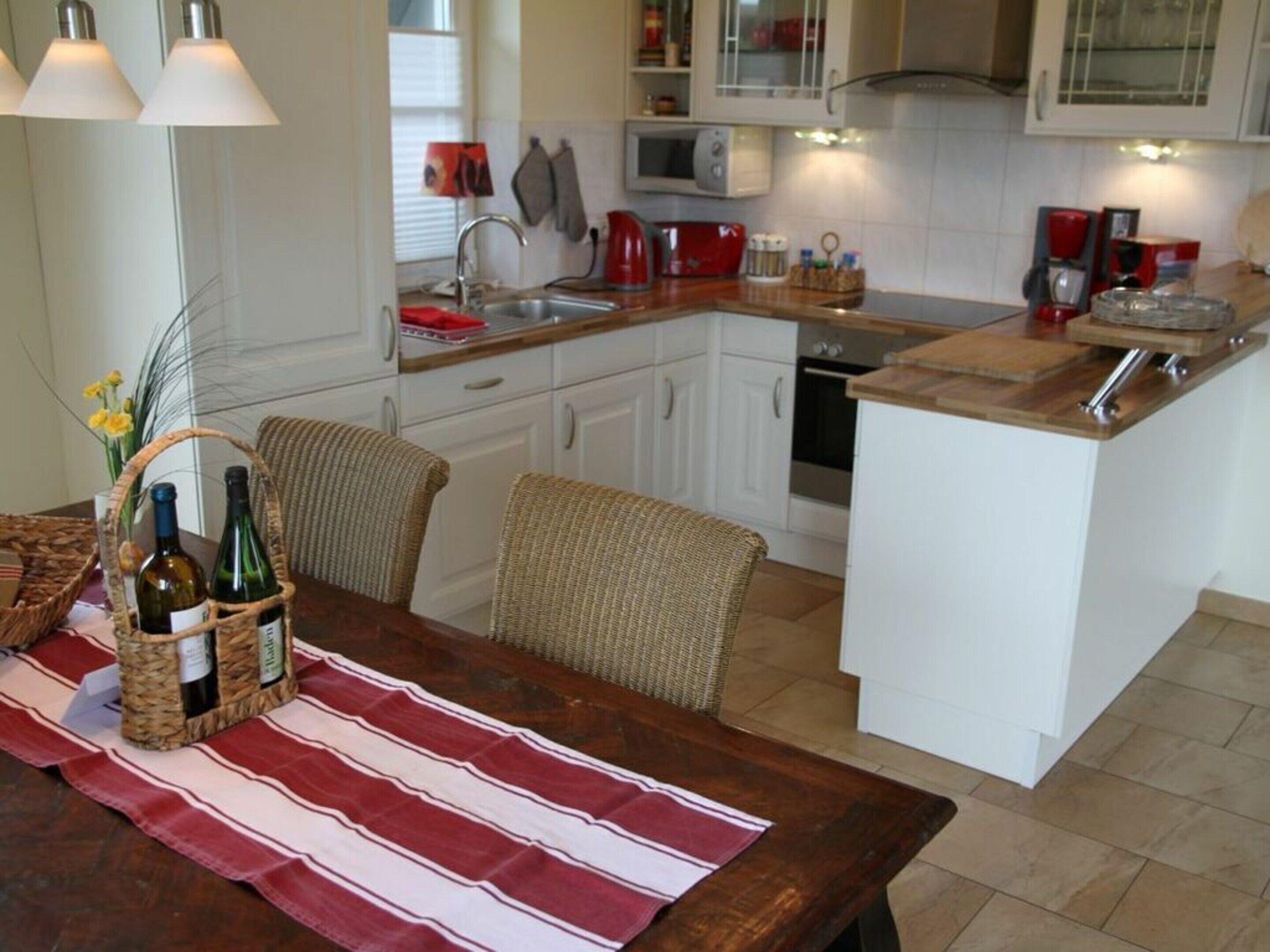 A modern kitchen with white cabinets, a wooden island, and a striped tablecloth.