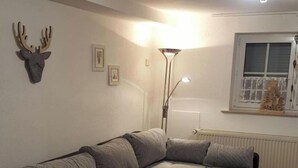 A cozy living room with a sectional sofa, a small round table, and a floor lamp. - Holiday Home Kobel Comfortable Vacation Home (Elmstein)