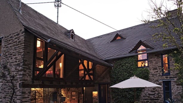 Un bâtiment en pierre doté d’un balcon en bois et d’un patio couvert.