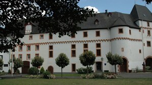 Un grand bâtiment blanc, doté de nombreuses fenêtres et d’une entrée centrale.