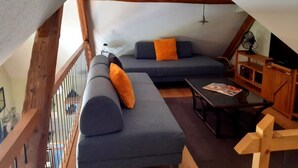 Un espace de vie chaleureux de style loft, doté d’un haut plafond, de poutres apparentes et d’un banc en bois intégré.