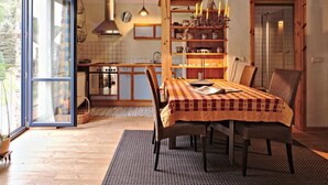 Un coin repas accueillant avec une table dressée pour quatre personnes, des chaises en bois et une nappe à motifs.
