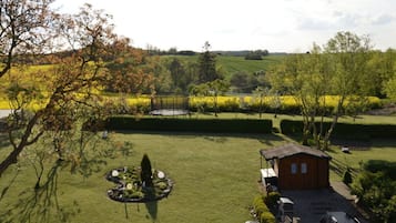 Uma área gramada com um jardim circular, uma cabana de madeira e um gazebo de metal.