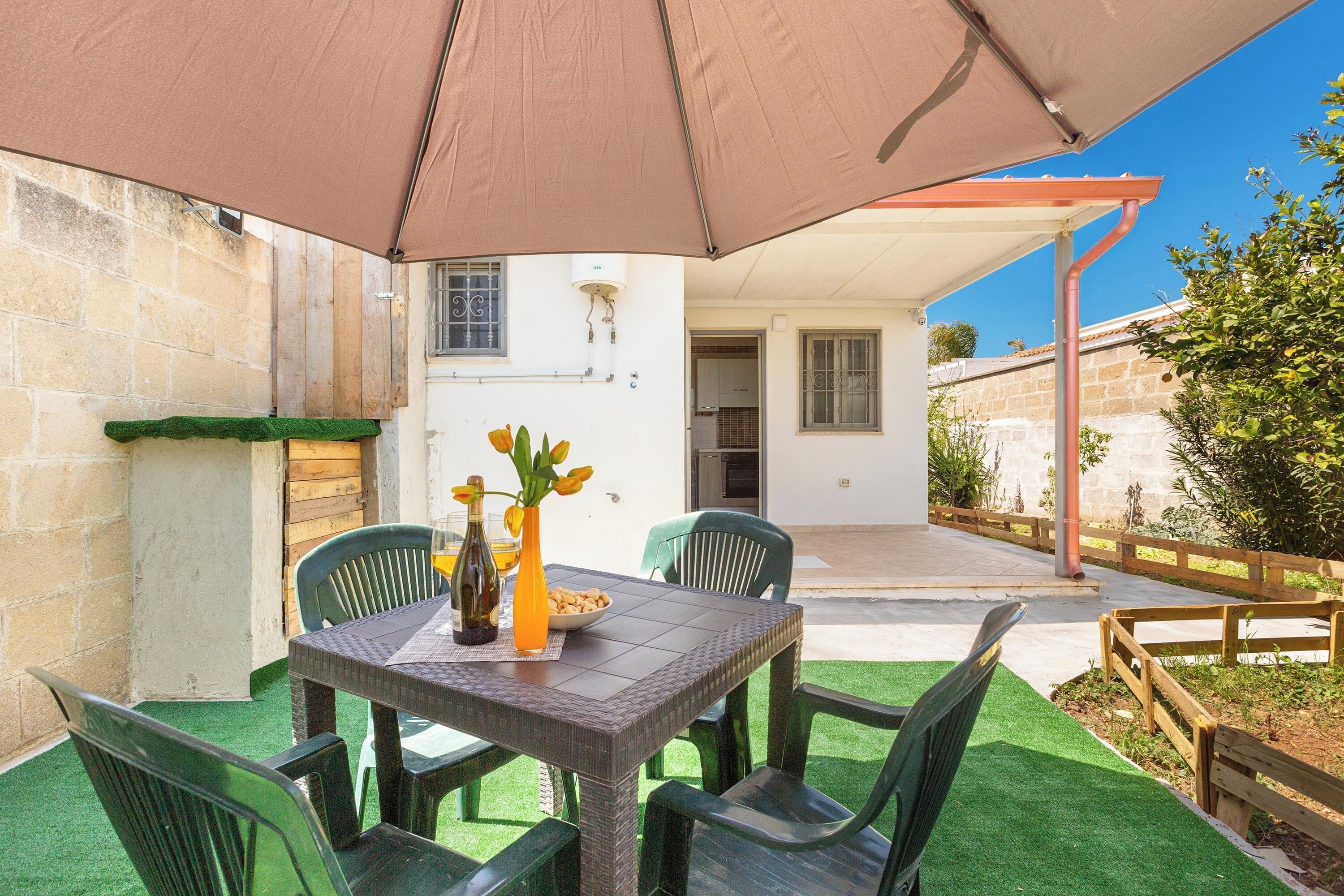 Une terrasse extérieure avec une table, des chaises et un parasol.