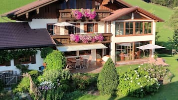 A two-story chalet with a balcony, a patio with outdoor furniture, and a well-maintained garden.