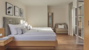 A modern bedroom with a large bed, a bedside table, a reading chair, and a wardrobe. - Holiday Apartment The Neuhaus (Abtenau)