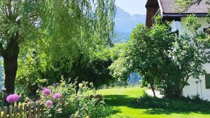 A house with a garden, a wooden fence, and a mountain in the background. - Holiday Apartment The Neuhaus (Abtenau)