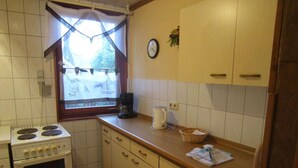 Una cocina pequeña con estufa, cafetera y ventana con vistas al exterior.
