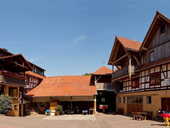 Un bâtiment traditionnel doté d’un porche, de balcons en bois et d’un toit recouvert de tuiles rouges.