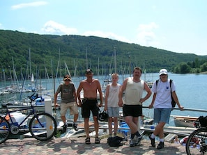 A group of people standing by a dock with boats and a bicycle.