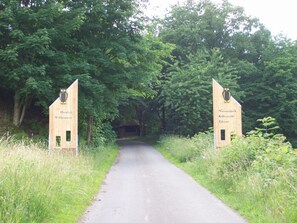 A pathway leading into a wooded area with two wooden signs on either side.