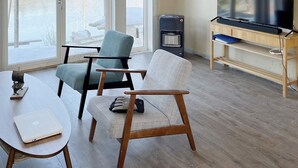 A living room with a TV, two chairs, a table, and a heater. - 8 Person Holiday Home in Seim (Alver)