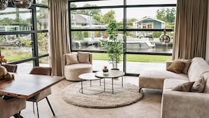 Un salon spacieux avec une grande fenêtre, une table basse ronde et un canapé.