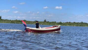 A boat on a calm lake with a person steering it.