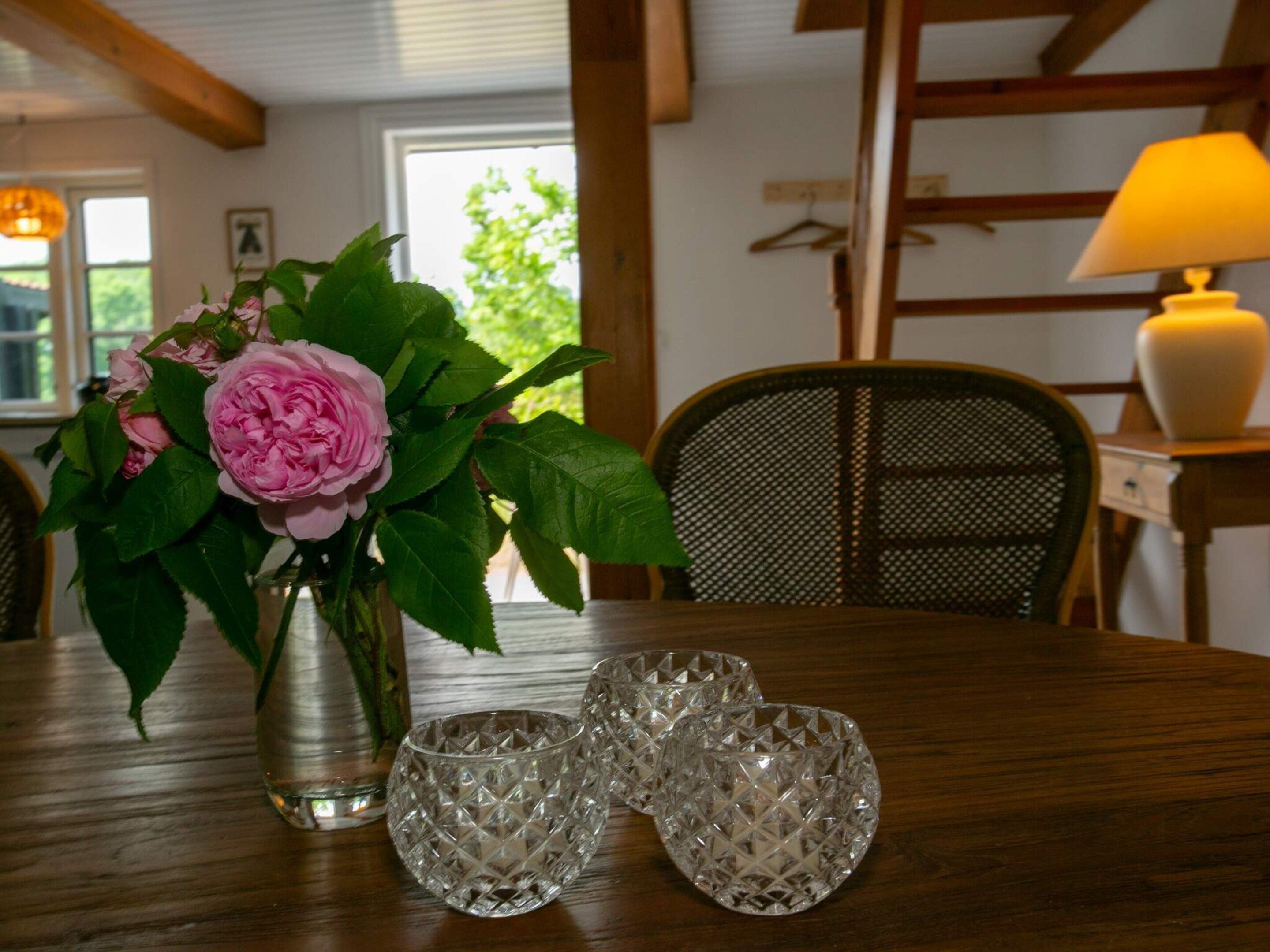 A dining table with a vase of flowers and crystal glasses.
