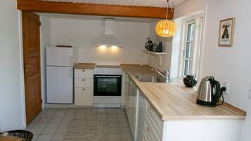 A compact kitchen with a refrigerator, oven, and sink.