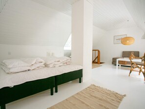 A bedroom with a bed, a sofa, a chair, a table, and a hanging light fixture. - 4 Person Holiday Home in Rudkobing (Rudkobing)