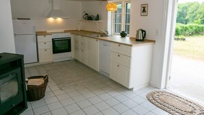 A kitchen with white cabinets, a stove, a sink, and a window. - 4 Person Holiday Home in Rudkobing (Rudkobing)