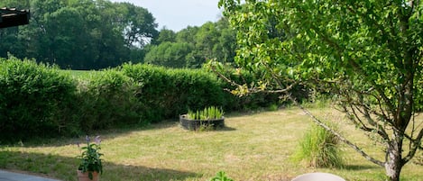 An outdoor seating area with a table and chairs, surrounded by greenery and a hedge.