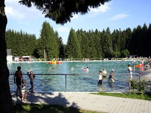 A public swimming pool with people swimming and walking around.