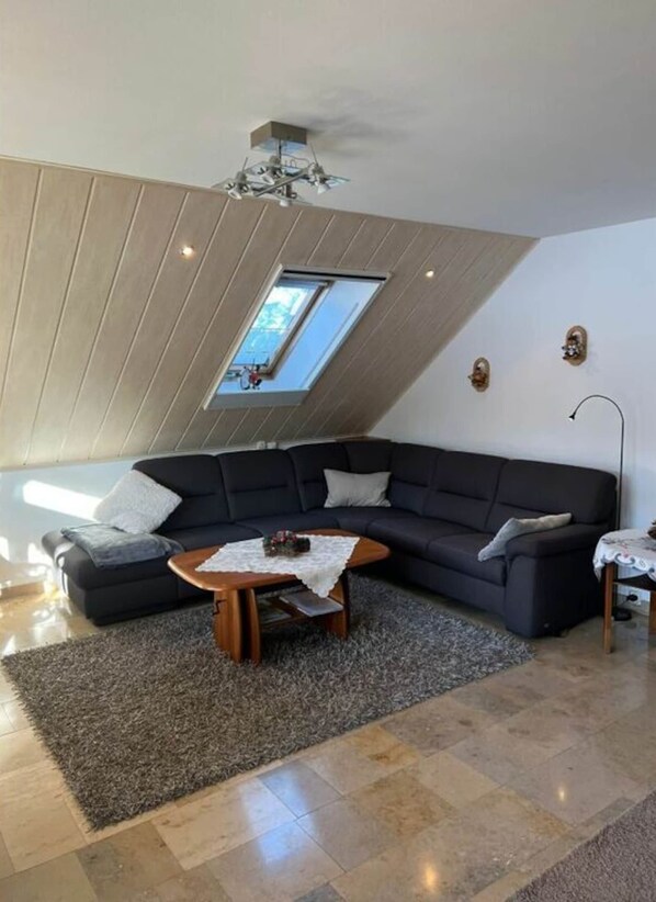 A modern living room with a sectional sofa, a wooden coffee table, and a skylight.