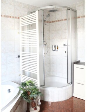 A corner shower with a glass door, a white towel rack, a sink, and a potted plant. - Holiday Apartment Pure Nature (Marienberg)