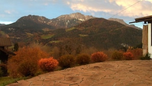 Une terrasse en pierre offrant une vue sur les montagnes et les couleurs automnales.