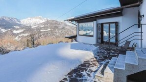 Un bâtiment moderne, avec un sol enneigé et une vue sur des montagnes aux sommets couverts de neige.