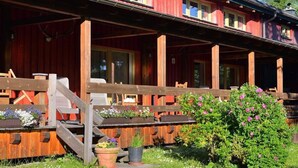 A wooden cabin with a covered porch, outdoor seating, and a small garden area. - Rasehorn Comfortable Holiday Residence (Altenberg)