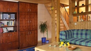 A cozy living room with a wooden staircase, a blue sofa, and a bookshelf. - Rasehorn Comfortable Holiday Residence (Altenberg)