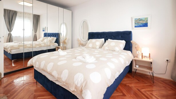 Une chambre à coucher avec un grand lit, un miroir, une table de chevet avec une lampe et un tableau au mur.