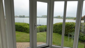 Une chambre d’angle dotée de grandes portes vitrées donnant sur un lac et une végétation luxuriante.