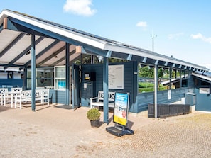 A building with a covered outdoor seating area, a small garden, and a signboard. - 5 Person Holiday Home in Aabenraa (Aabenraa)