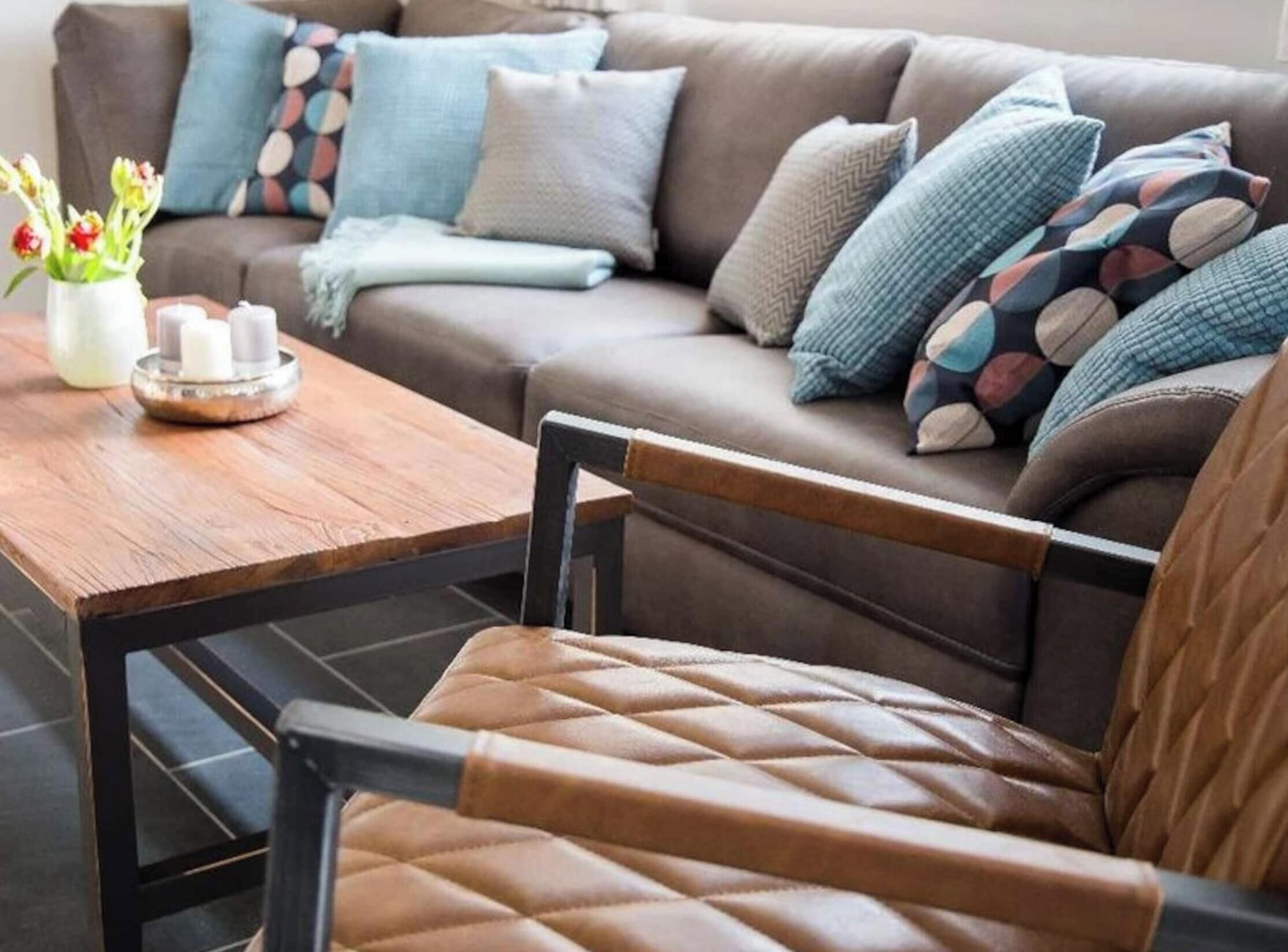 A cozy living room with a brown leather sofa, a wooden coffee table, and a chair with a leather seat.
