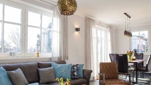 A modern living room with a brown leather sofa, a wooden coffee table, and a dining area with a table and chairs. - House Summerlove Comfortable Vacation Home (Ostseebad Prerow)