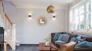 A modern living room with a brown leather sofa, a coffee table, and a decorative mirror on the wall. - House Summerlove Comfortable Vacation Home (Ostseebad Prerow)