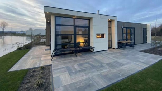 Una casa moderna con un patio, chimenea y vistas a un cuerpo de agua.
