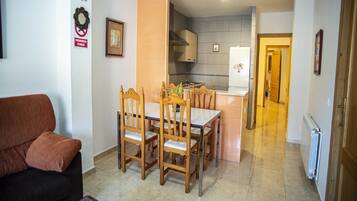 Una sala de estar con sofá y un comedor con sillas de madera y una mesa.