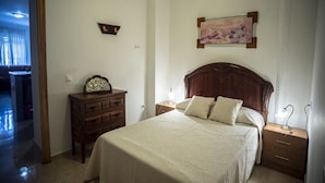 A bedroom with a large bed, wooden headboard, bedside tables, a dresser, and a painting on the wall.