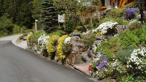 A house with a red-tiled roof, surrounded by a lush garden with various flowers and plants. - Oberrain in het "vakantiehuis Schenk" (Baiersbronn)