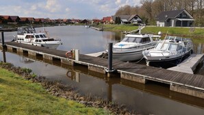 A marina with boats docked at wooden piers, surrounded by houses and a grassy area. - Marinapark 147 Modern Retreat (Walchum)