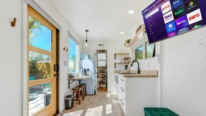 Una cocina moderna con un amplio ventanal, un comedor y un televisor que muestra servicios de streaming.